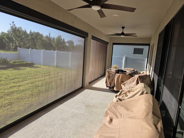 sunroom / solarium with a ceiling fan and carpet flooring