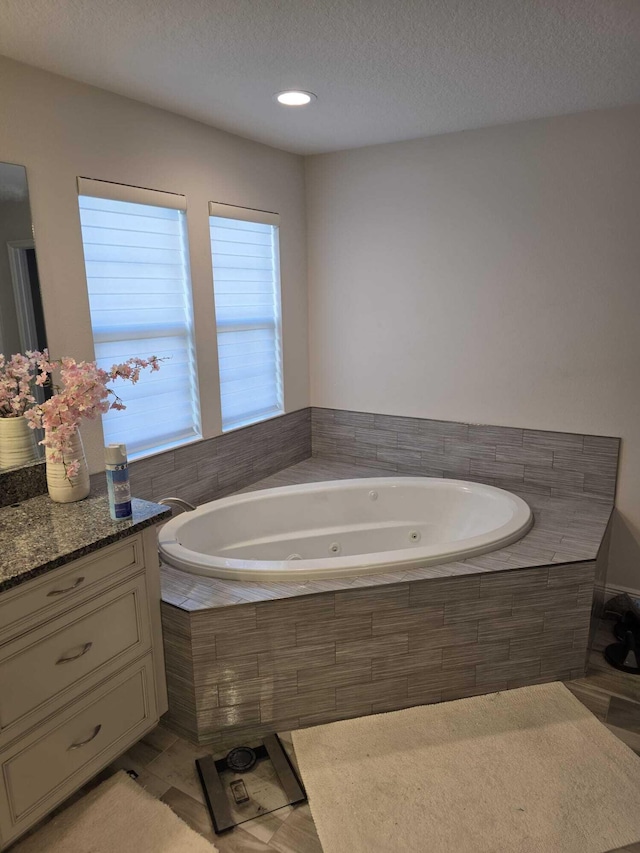 bathroom with a jetted tub, vanity, and a textured ceiling