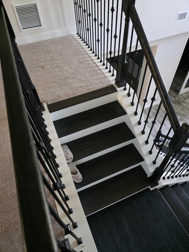 stairs with baseboards, visible vents, and wood finished floors