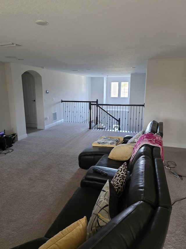 carpeted living area with arched walkways, baseboards, and visible vents