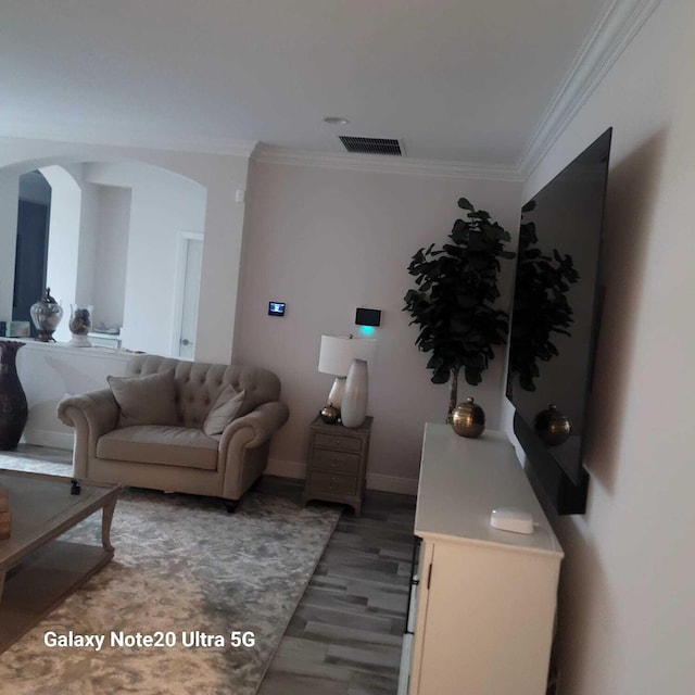 living room with arched walkways, ornamental molding, light wood-style flooring, and visible vents