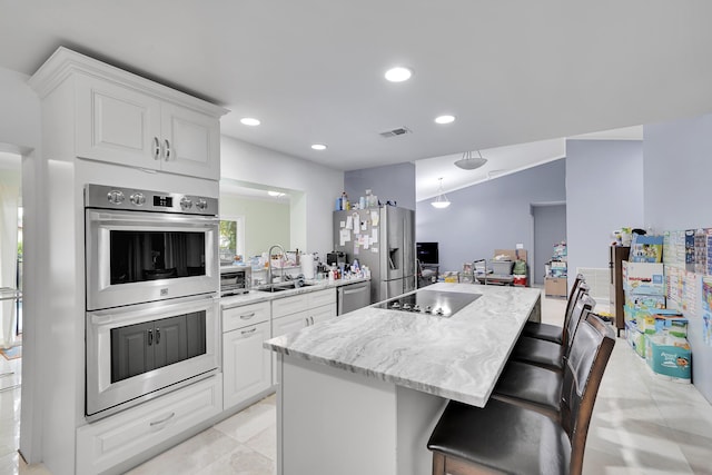 kitchen with visible vents, a center island, a sink, stainless steel appliances, and white cabinetry