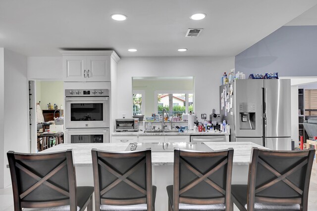 kitchen featuring visible vents, a toaster, white cabinetry, a sink, and stainless steel appliances