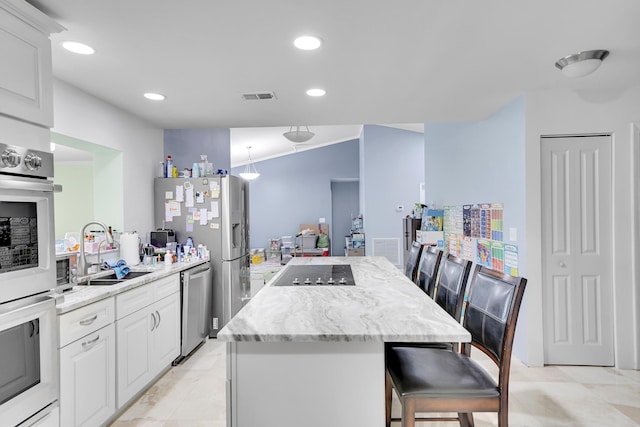 kitchen featuring visible vents, stainless steel dishwasher, a center island, black electric cooktop, and a sink