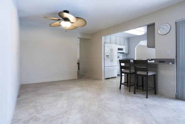 185 Bilbao St, Royal Palm Beach, FL 33411 - kitchen with baseboards, a ceiling fan, white appliances, and a kitchen bar