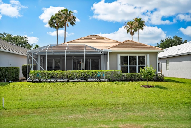 back of house featuring a tiled roof, a lawn, stucco siding, and a lanai