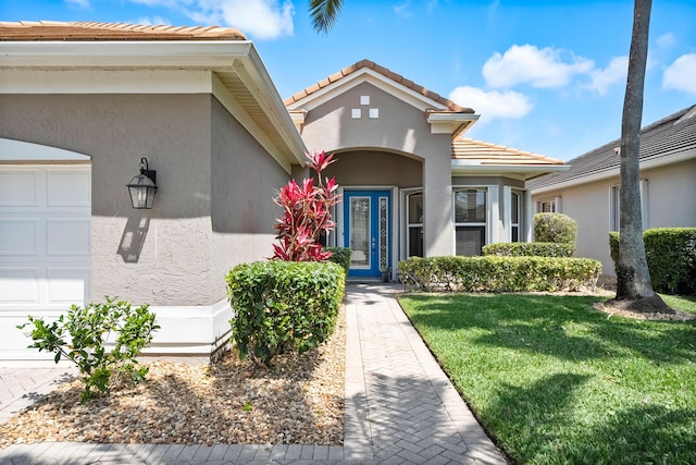 view of front of house featuring driveway, a garage, stucco siding, a front lawn, and a tile roof