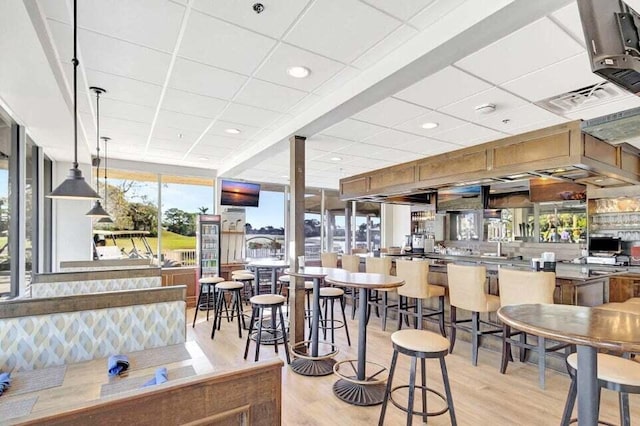 dining space with light wood finished floors and a drop ceiling