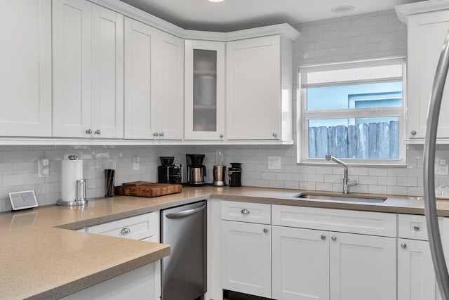 kitchen featuring stainless steel dishwasher, decorative backsplash, white cabinets, and a sink