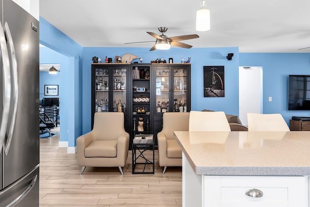living area with light wood-style flooring and a ceiling fan