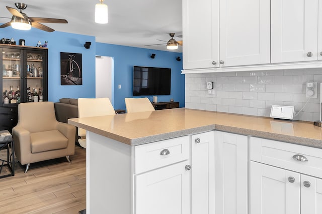 kitchen featuring a peninsula, tasteful backsplash, ceiling fan, white cabinetry, and open floor plan