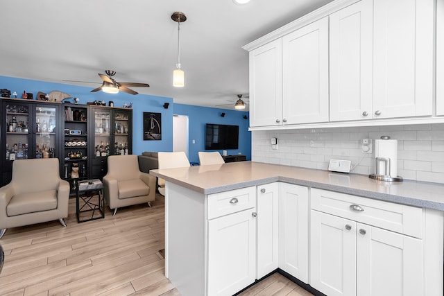 kitchen featuring a ceiling fan, a peninsula, open floor plan, and tasteful backsplash