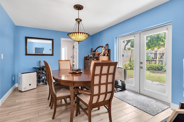 dining area featuring baseboards, light wood-type flooring, and french doors
