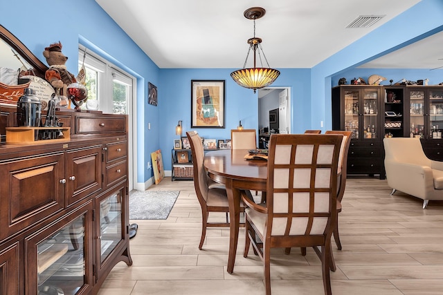 dining area featuring visible vents, light wood-style flooring, and baseboards