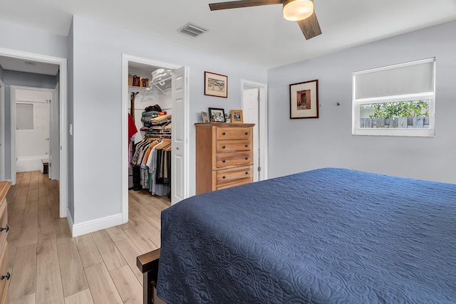 bedroom with visible vents, ceiling fan, light wood-style flooring, a walk in closet, and baseboards