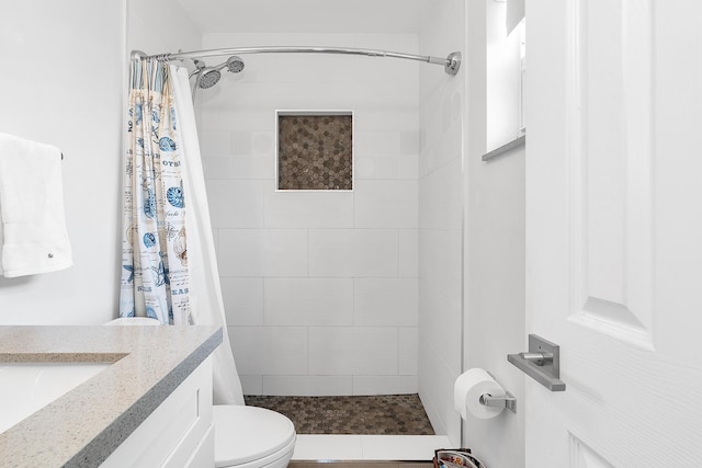 full bath featuring vanity, toilet, and tiled shower