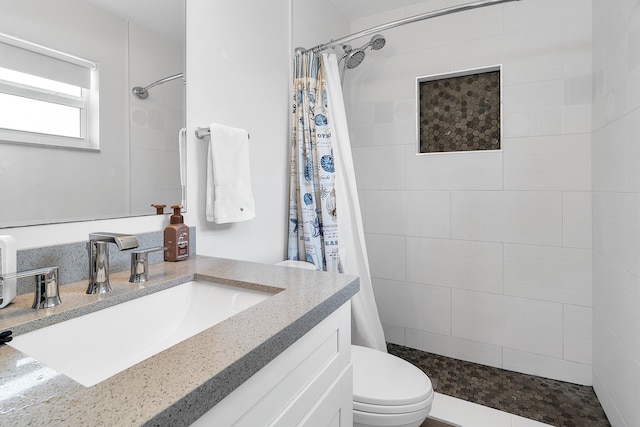 bathroom featuring vanity, toilet, and tiled shower