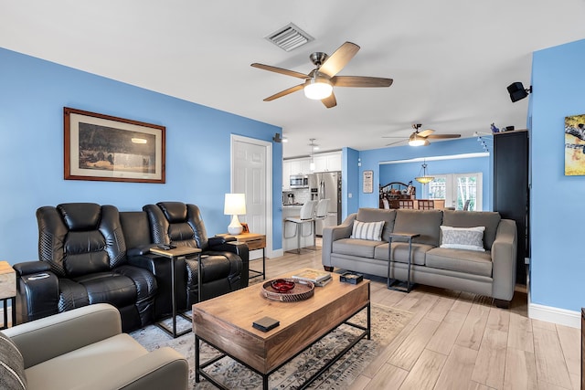 living room featuring baseboards, ceiling fan, light wood-style flooring, and visible vents