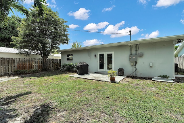 back of house featuring a yard, french doors, fence, a patio area, and stucco siding