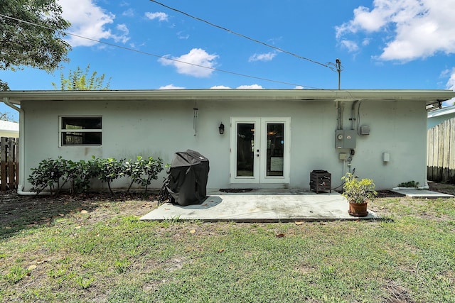 back of house with fence, stucco siding, french doors, and a lawn