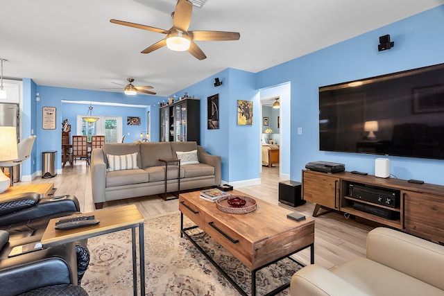 living room featuring ceiling fan, baseboards, and light wood-type flooring