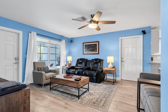 living room with baseboards, a ceiling fan, visible vents, and light wood-style floors