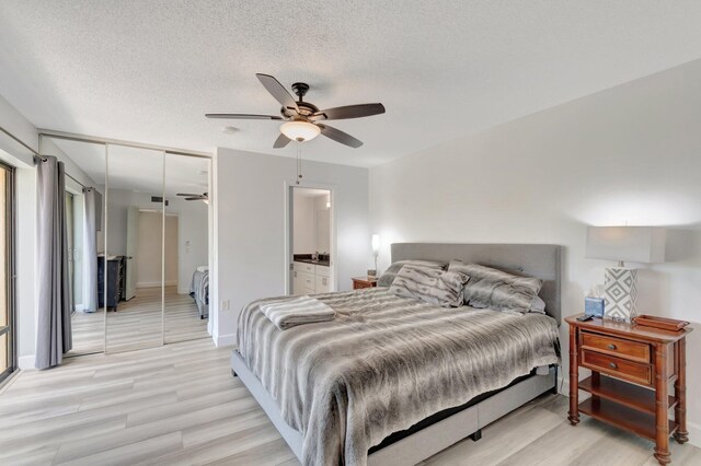 bedroom with light wood-type flooring, a closet, baseboards, a textured ceiling, and ceiling fan