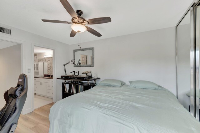 bedroom featuring light wood-style flooring, ensuite bathroom, a ceiling fan, and a closet