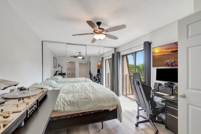 bedroom with access to outside, light wood-type flooring, an office area, a textured ceiling, and a ceiling fan