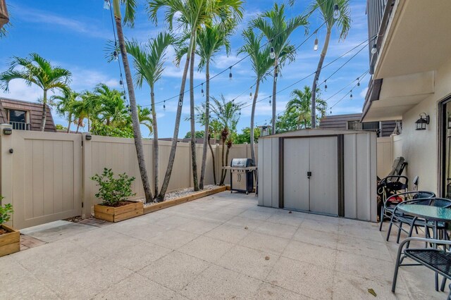 view of patio / terrace featuring a storage shed, a fenced backyard, an outdoor structure, and grilling area