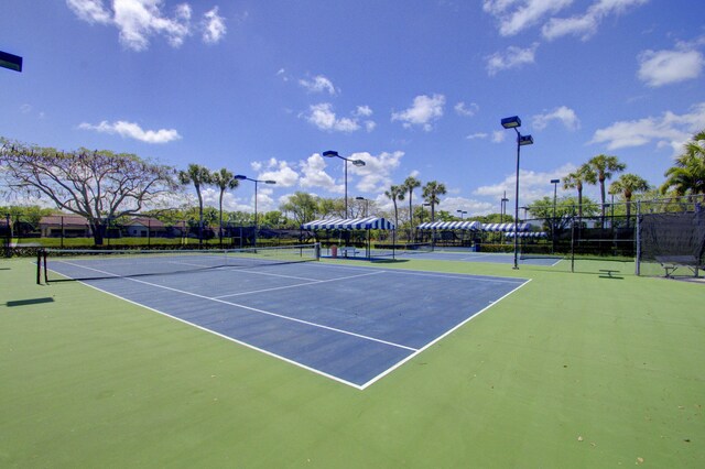 view of tennis court with community basketball court and fence