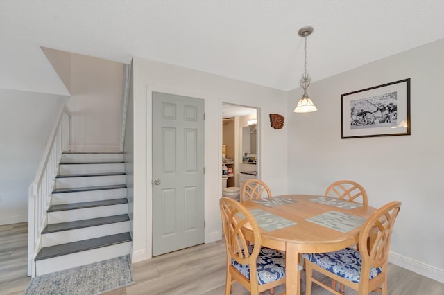 dining space with stairs, light wood-style floors, and baseboards