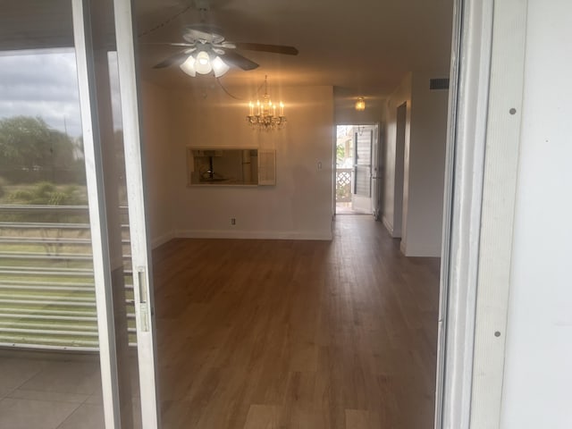 corridor featuring baseboards, a notable chandelier, wood finished floors, and visible vents
