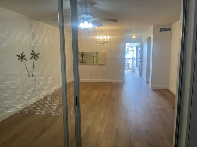 hallway featuring baseboards, a chandelier, wood finished floors, and visible vents