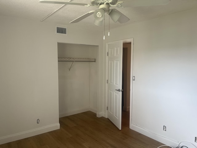 unfurnished bedroom with baseboards, a closet, wood finished floors, and visible vents
