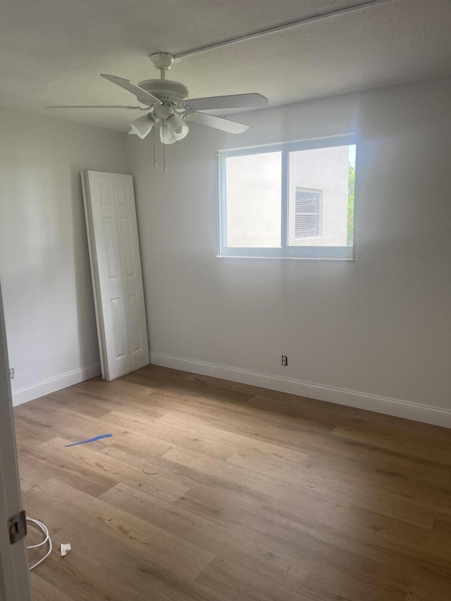 unfurnished room with baseboards, light wood-style flooring, and ceiling fan