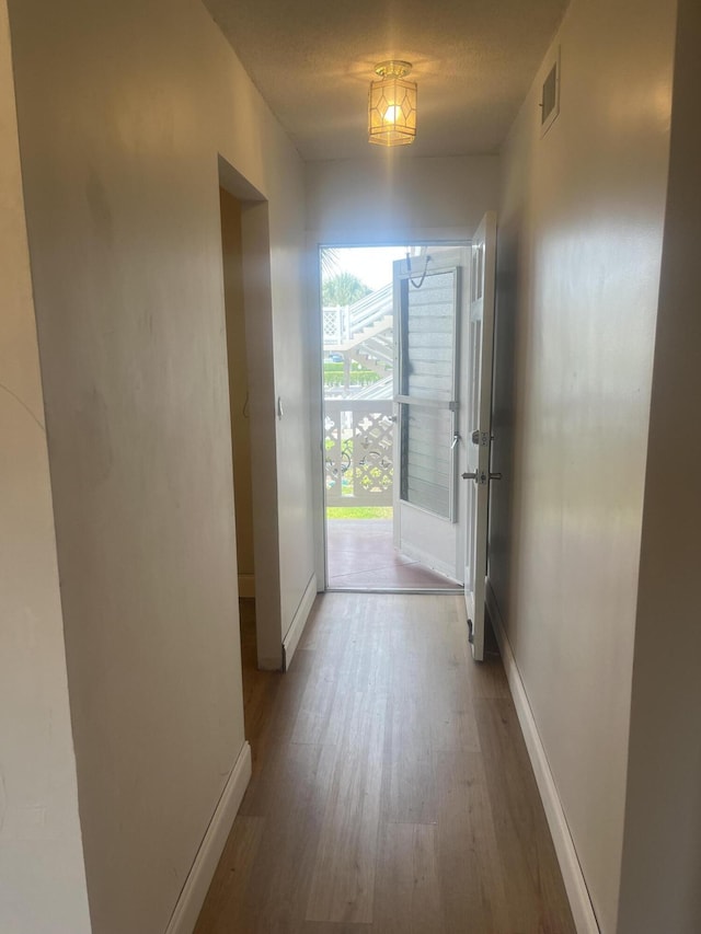 corridor with visible vents, baseboards, and wood finished floors