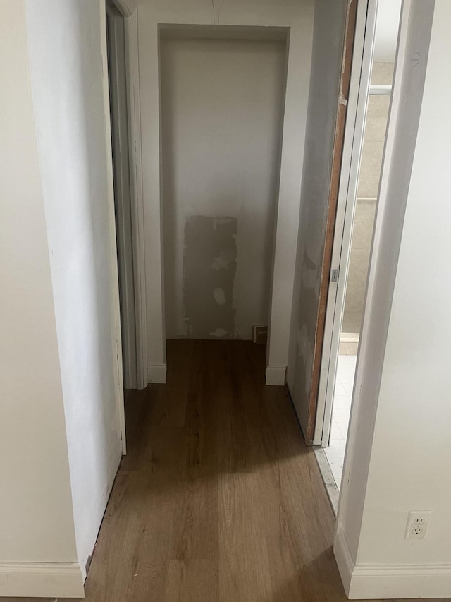 hallway with baseboards and wood finished floors