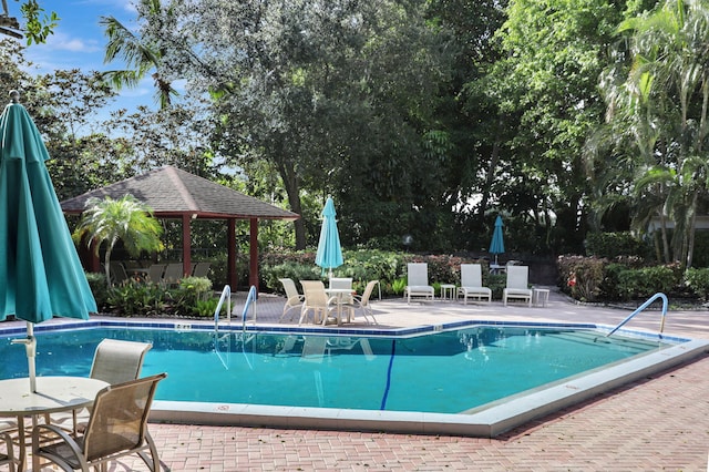 community pool featuring a gazebo, outdoor dining area, and a patio area