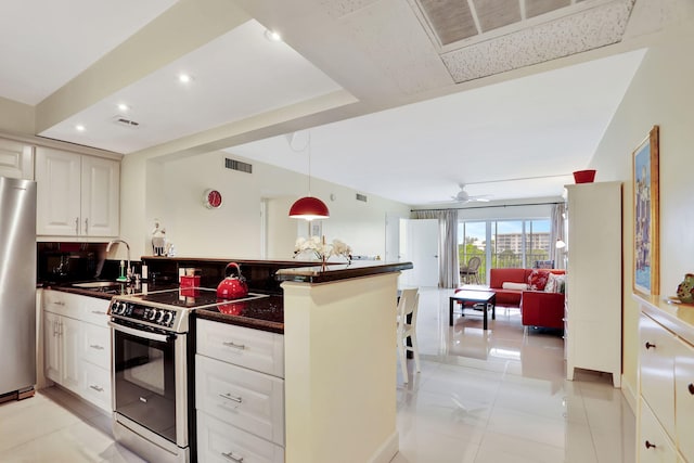 kitchen with visible vents, dark countertops, appliances with stainless steel finishes, a sink, and open floor plan