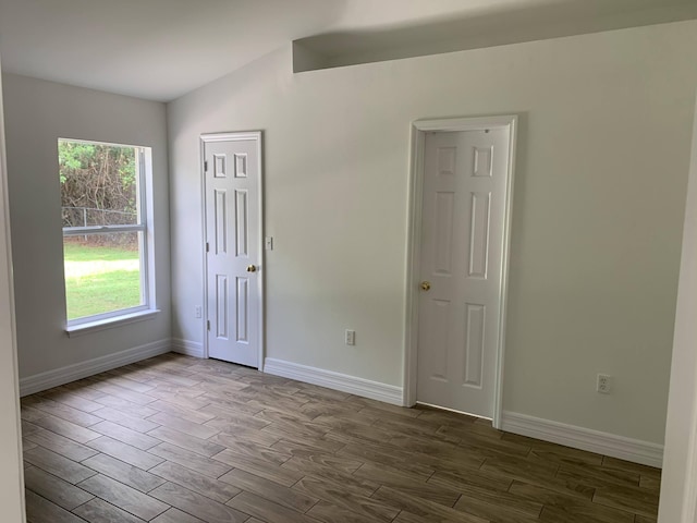 empty room featuring baseboards, a healthy amount of sunlight, and dark wood-style floors