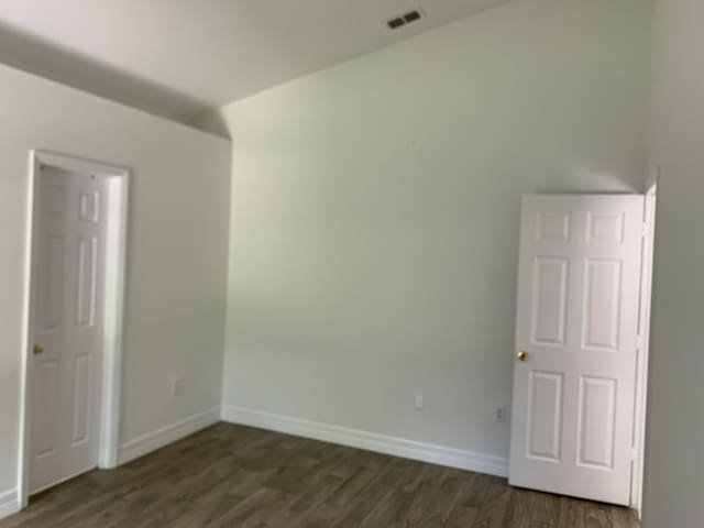 spare room with baseboards, dark wood-style floors, and visible vents