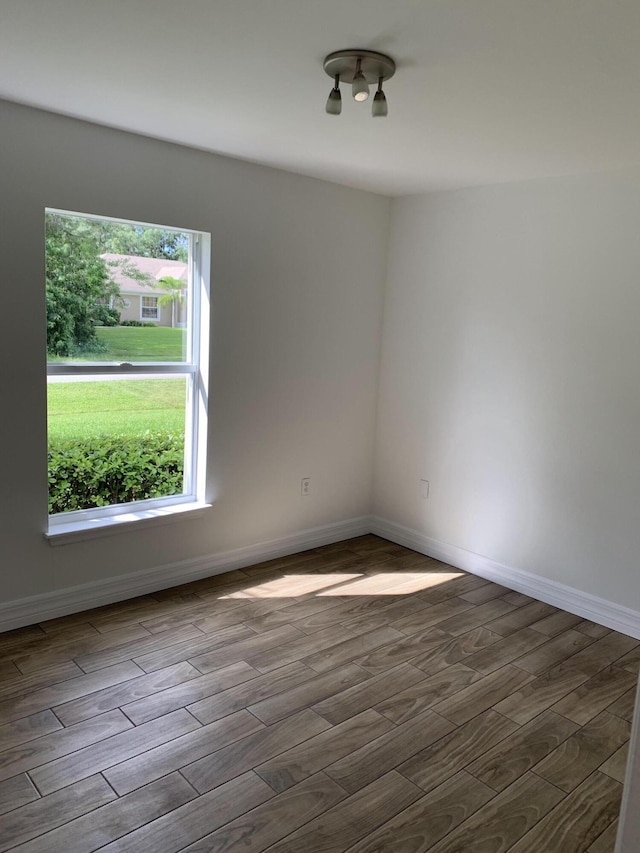 spare room featuring dark wood-style flooring and baseboards