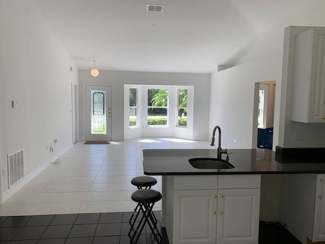 kitchen featuring a sink, dark countertops, white cabinets, and visible vents