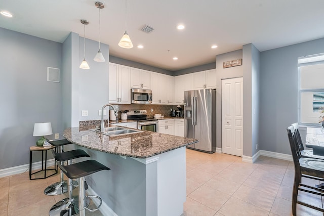 75 Atlantic Grove Way, Delray Beach, FL 33444 - kitchen featuring appliances with stainless steel finishes, a sink, a peninsula, dark stone countertops, and a breakfast bar