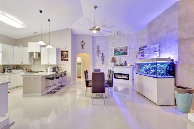 interior space with ceiling fan, light tile patterned flooring, arched walkways, and a glass covered fireplace