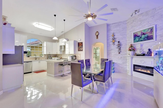 dining area featuring high vaulted ceiling, visible vents, arched walkways, a ceiling fan, and a glass covered fireplace