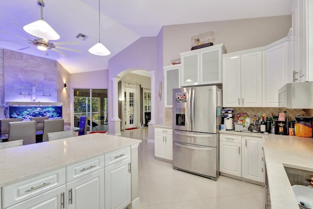 kitchen featuring stainless steel fridge, ornate columns, ceiling fan, arched walkways, and vaulted ceiling