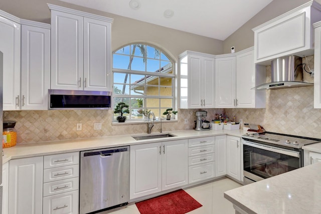 kitchen featuring wall chimney range hood, appliances with stainless steel finishes, white cabinetry, and a sink