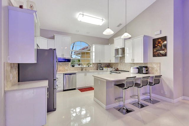 kitchen with a peninsula, appliances with stainless steel finishes, a sink, and tasteful backsplash
